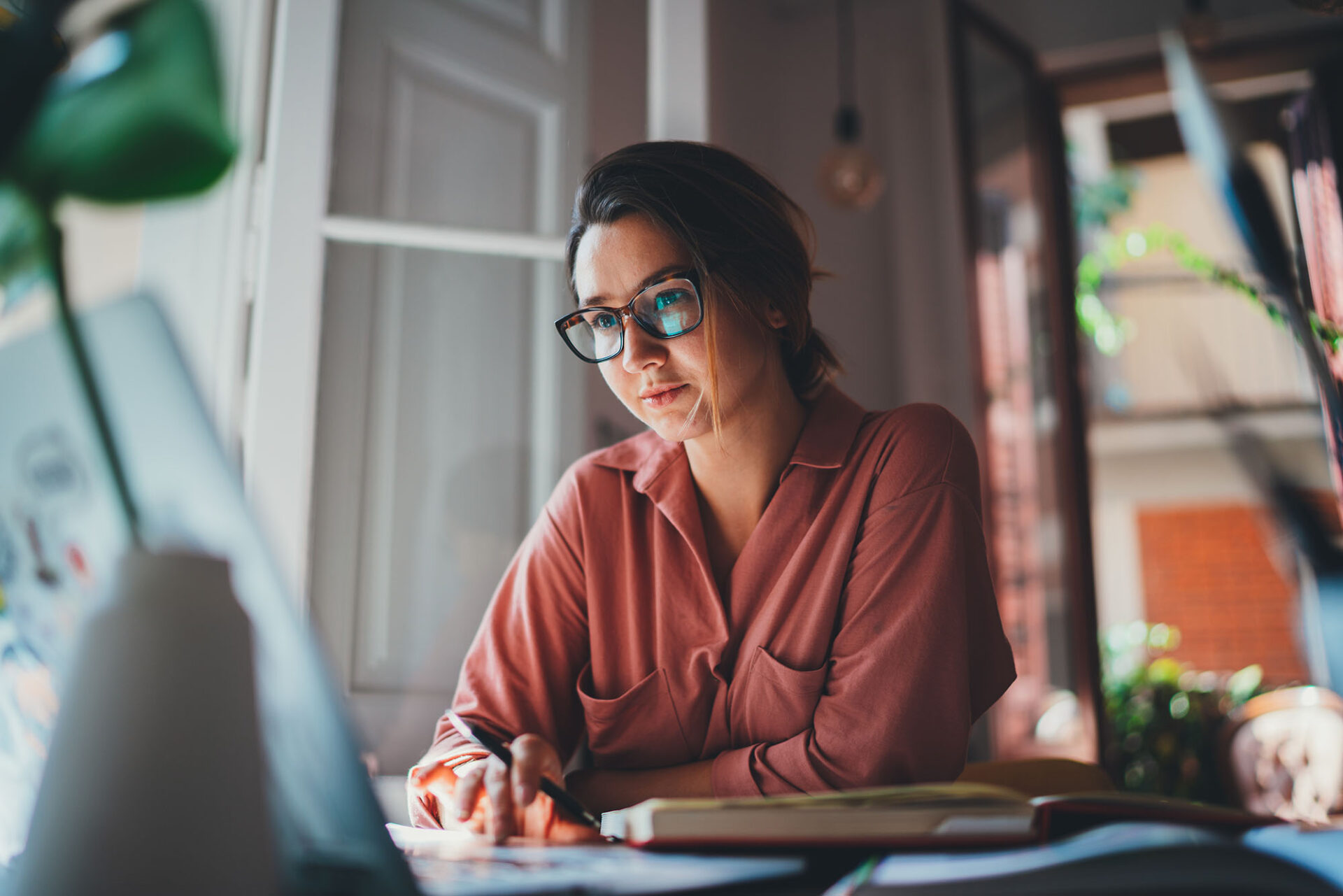 Finance professional on business call while reviewing journal entry accounting tasks on laptop
